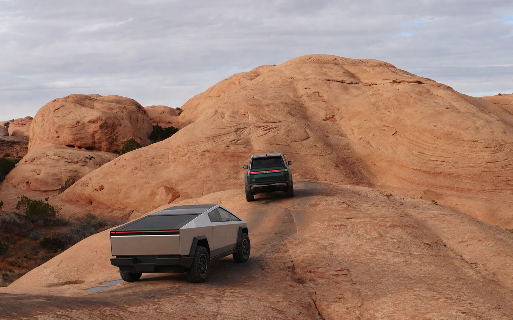 A Cybertruck and Rivian R1S climbing Baby Lion's Back near Moab