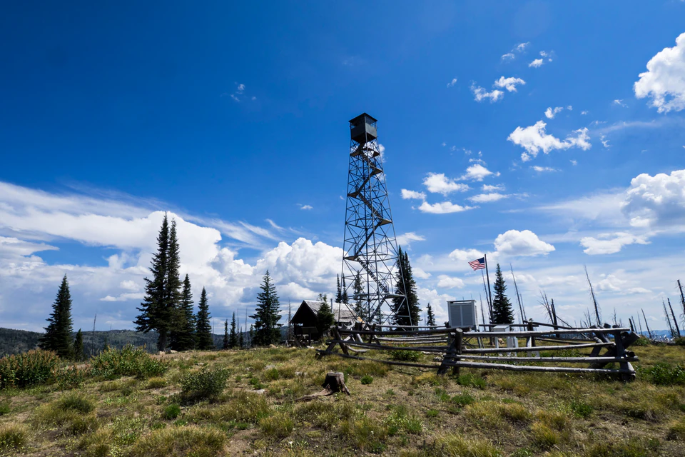 Steel Carey Dome fire lookout and summit cabin beneath broad summer clouds.