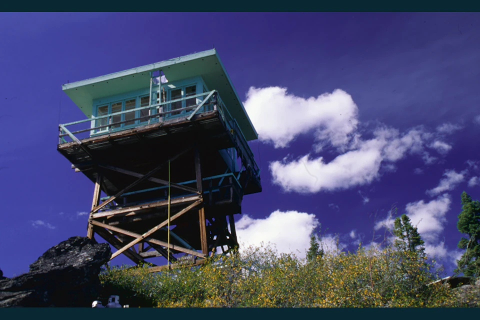 Wooden Flag Point fire lookout beneath a deep blue sky and white clouds.