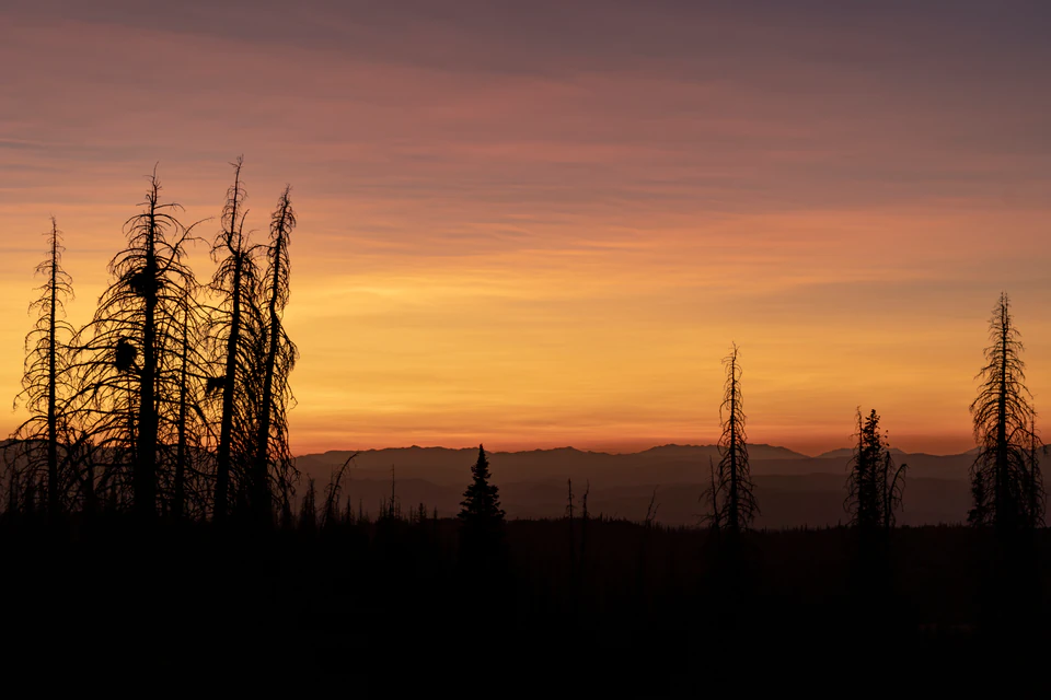 Orange sunset light spreading across layered Wasatch ridges from Heber Mountain.
