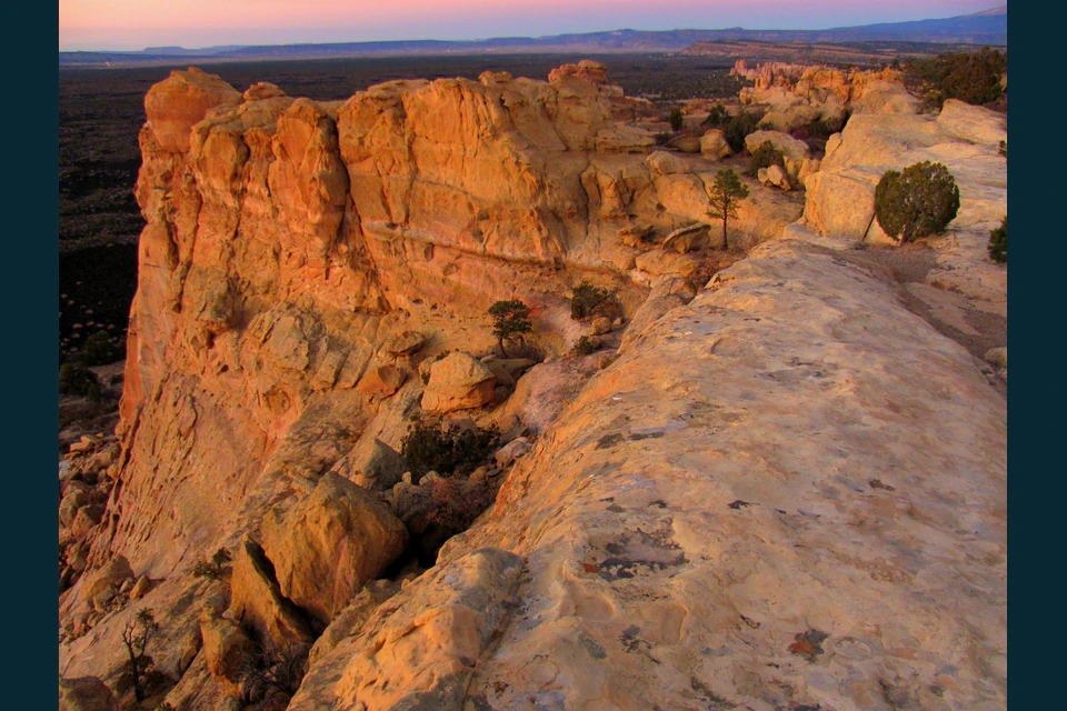 Warm twilight over pale sandstone cliffs and dark lava country at Sandstone Bluffs Overlook.